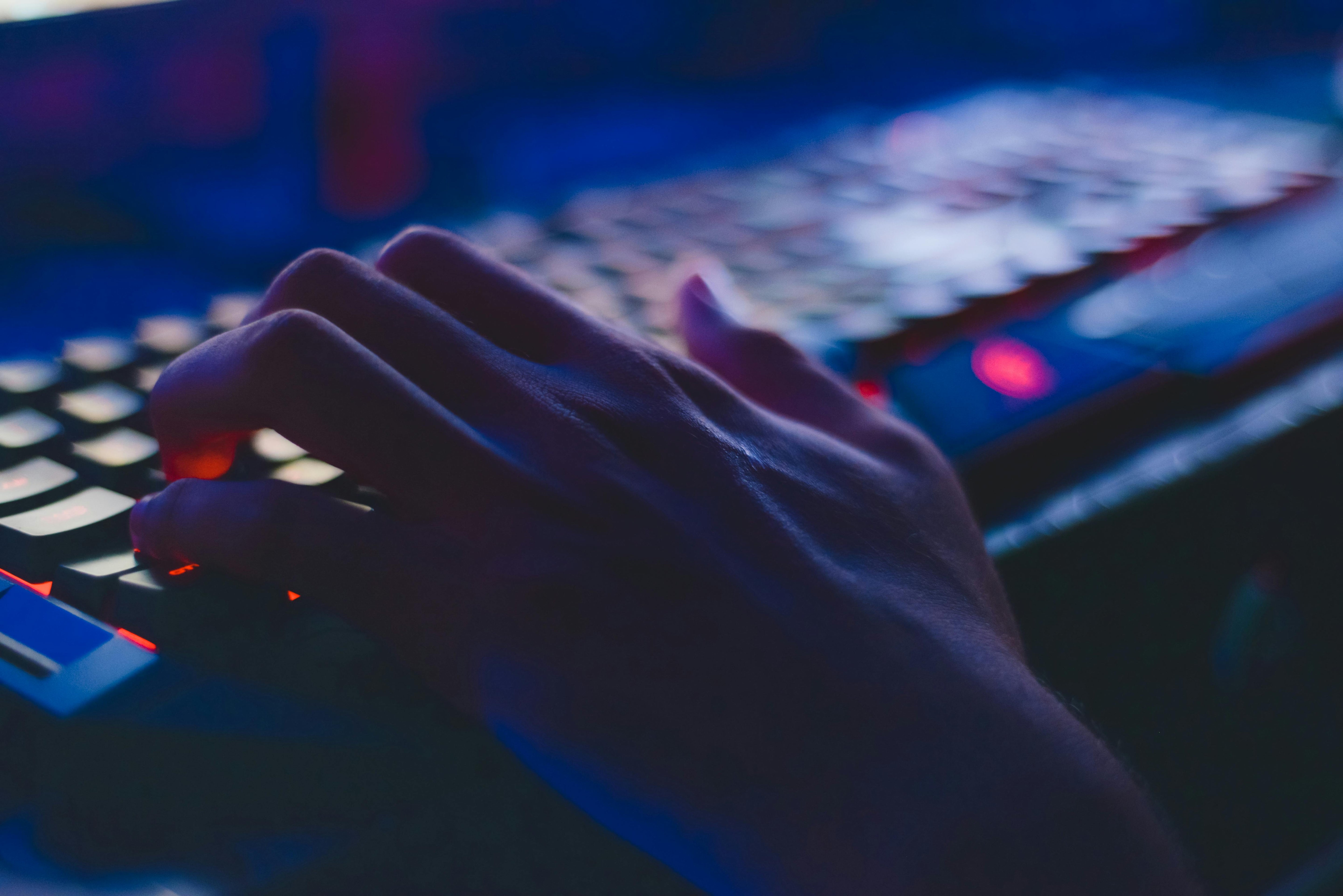 Picture showing a person playing video games with a gaming keyboard.