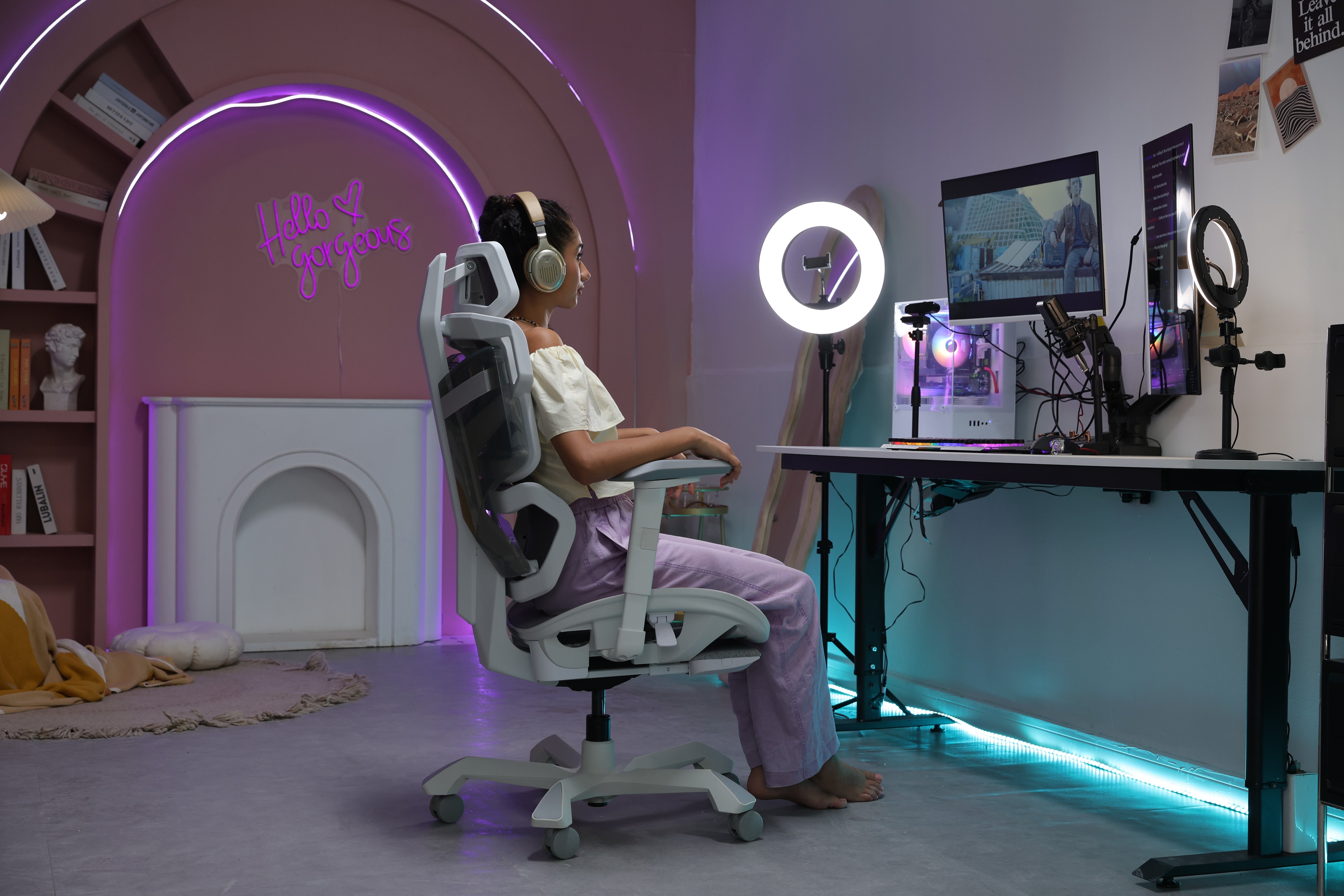 Picture showing the TGIF Home White from the side with a person sitting on it and watching something on the screen