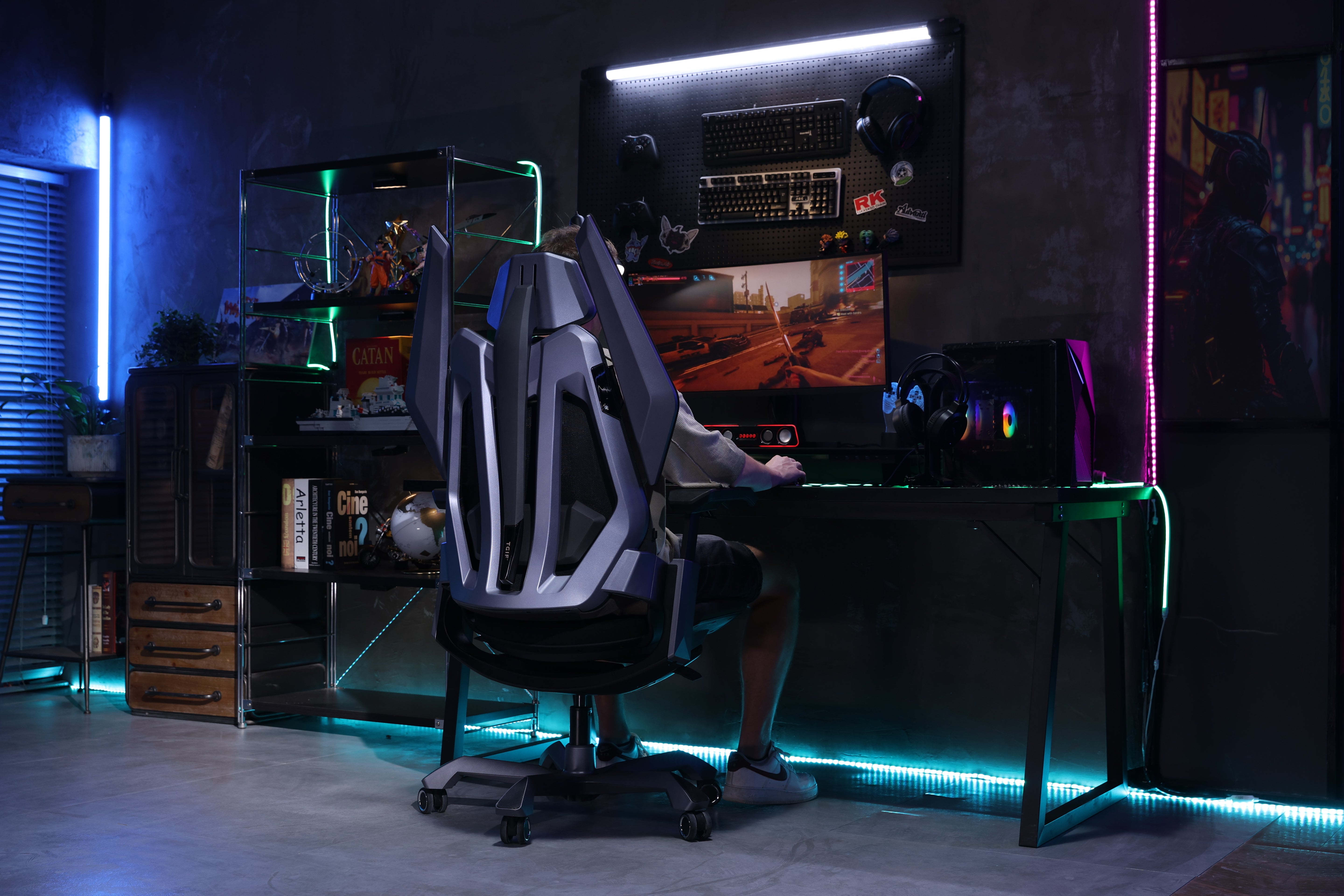 Picture showing the TGIF T0 from the back with a person sitting on it and playing video games. 